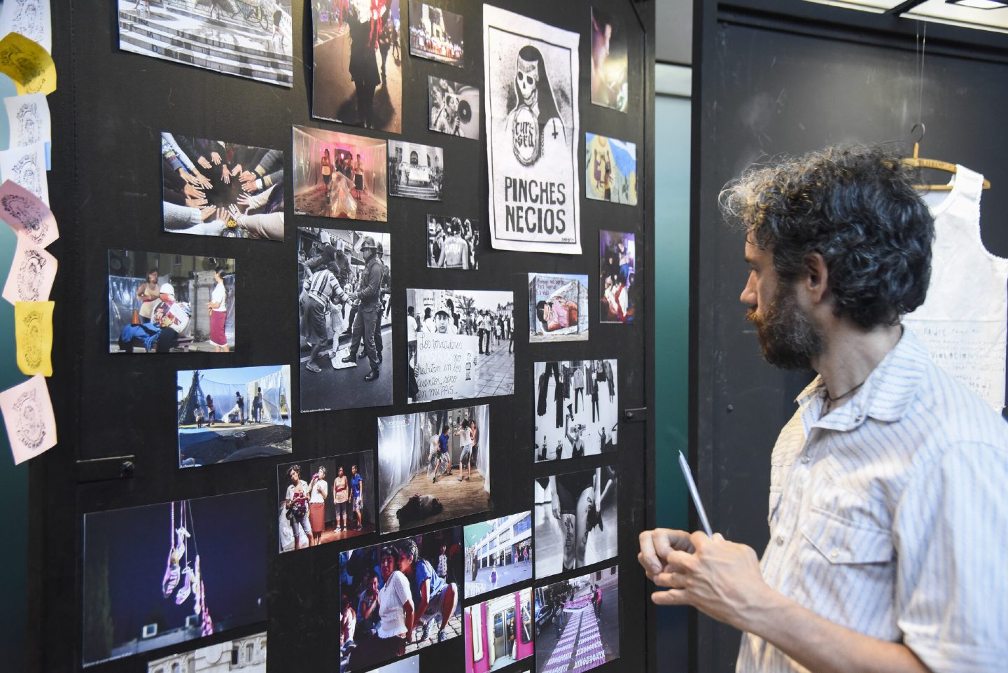 A visitor studies a wall of photographs, prints and zines documenting feminist protest across Latin America.
