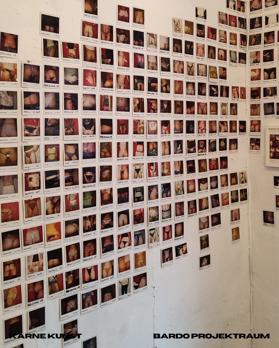 Hundreds of small annotated photographs of bodies pinned in a dense grid that covers a gallery wall and continues around the corner.